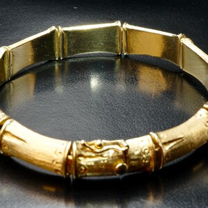 May include: A gold bamboo-style bangle bracelet with a textured finish.