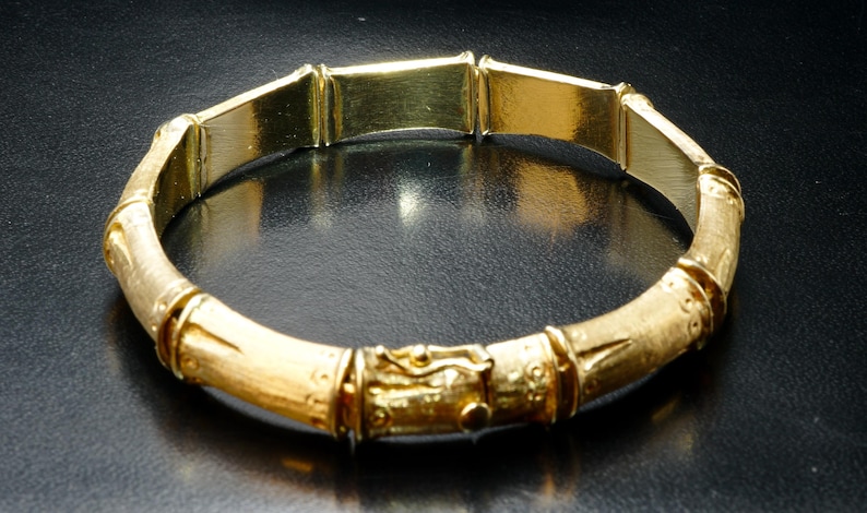 May include: A gold bamboo-style bangle bracelet with a textured finish.