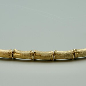 May include: A gold bamboo-style bangle bracelet.
