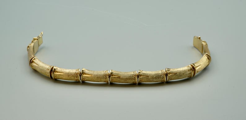 May include: A gold bamboo-style bangle bracelet.