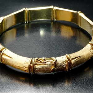 May include: A gold bamboo-style bangle bracelet with a textured finish.