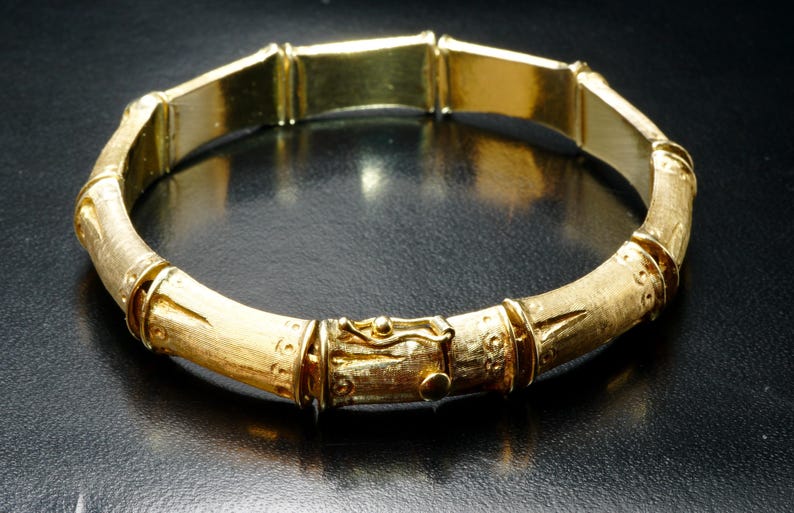 May include: A gold bamboo-style bangle bracelet with a textured finish.