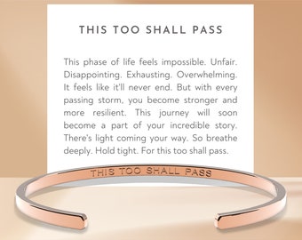 May include: Rose gold bangle bracelet with the inscription "This too shall pass".