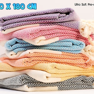 May include: A stack of eight Turkish towels in various colours, including purple, pink, blue, orange, yellow, and black. The towels are 100 x 180 cm and are described as ultra soft and pre-washed.