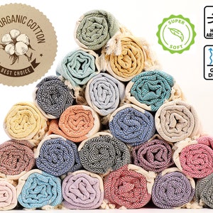 May include: A stack of 20 colorful Turkish towels, rolled up and arranged in a pyramid shape. The towels are made of 100% organic cotton and are labeled as "Super Soft" and "Highly Absorbent".