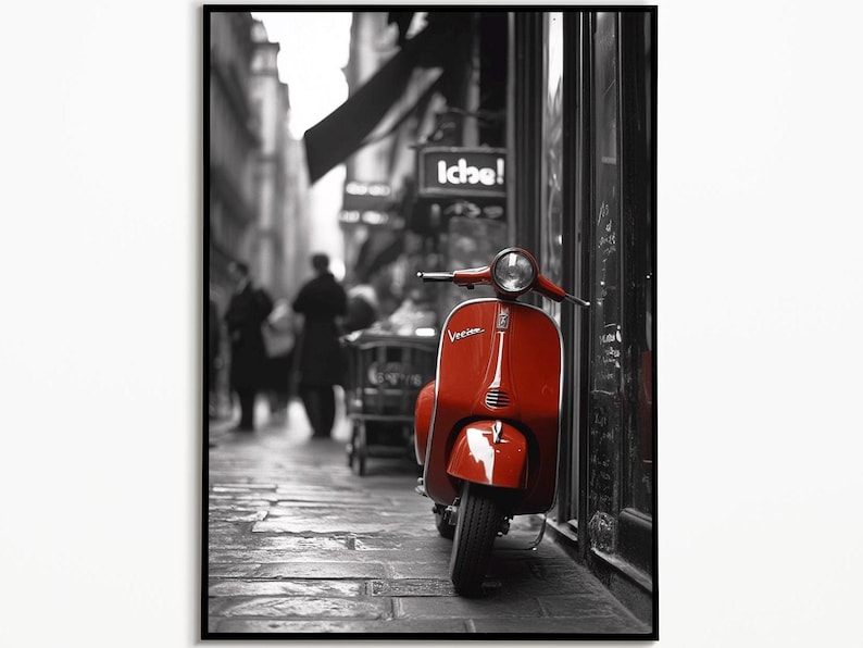 May include: A red Vespa scooter parked on a cobblestone street in a black and white city setting. The scooter is parked next to a building with a sign that reads "Iche!" in black and white.