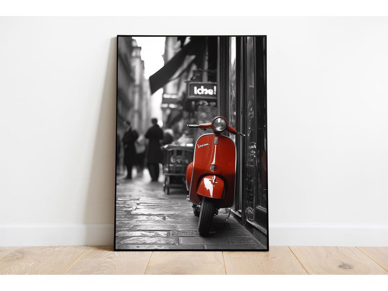 May include: A red Vespa scooter parked on a cobblestone street in a black and white city setting. The scooter is the only color in the image.