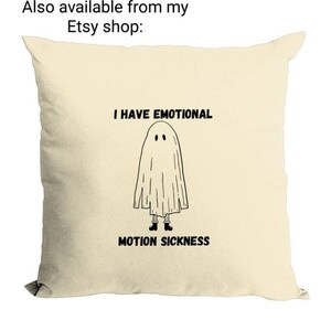 May include: A cream-colored pillow with a black and white illustration of a ghost with the text "I have emotional motion sickness".