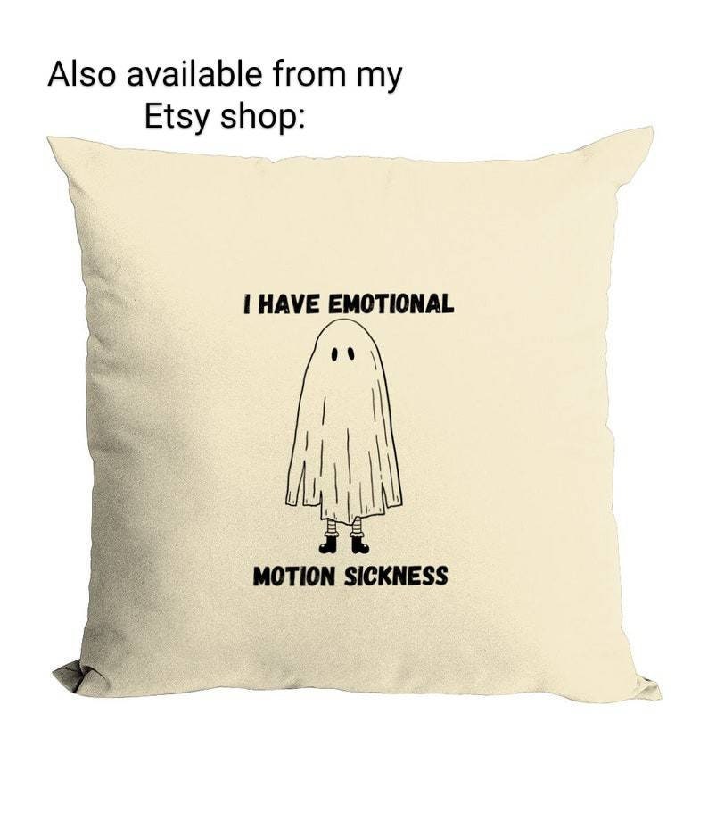 May include: A cream-colored pillow with a black and white illustration of a ghost with the text "I have emotional motion sickness".