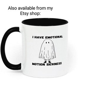 May include: White coffee mug with a black rim and handle. The mug has a black and white illustration of a ghost with the text "I have emotional motion sickness".