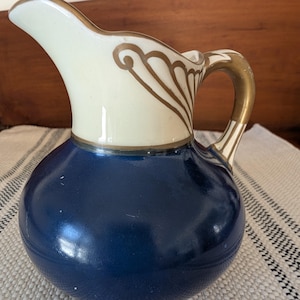 Peut inclure: Ensemble de trois mugs en céramique avec une finition mate et mouchetée. Les tasses sont de couleur crème, gris clair et gris foncé. Chaque mug a un design simple et minimaliste.