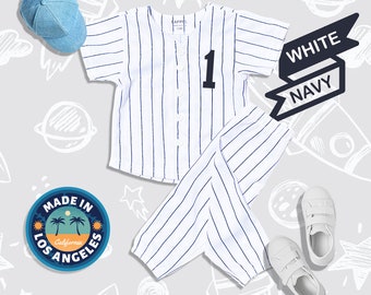 May include: White and navy blue striped baseball jersey and pants set with the number "1" on the front of the jersey. The set is made in Los Angeles, California.