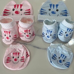 May include: A set of baby booties and mittens featuring a cute cat design. The booties and mittens are available in pink and blue with white polka dots. The cat design has a pink nose and whiskers on the pink set and a blue nose and whiskers on the blue set.