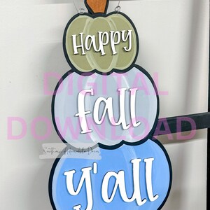 May include: A three-tiered pumpkin sign with the words "Happy fall y'all" painted in white on a blue, gray, and green background.