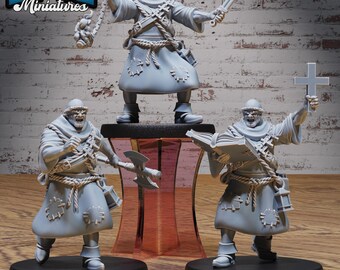 以下が含まれることがあります： 中世のキャラクターの3つの灰色のミニチュアフィギュア。1つのフィギュアは剣とフレイルを持ち、もう1つは斧、3つ目は十字架と本を持っています。フィギュアは黒いベースにあり、左上隅に「EPIC Miniatures」というテキストがあります。