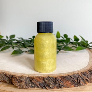 May include: A small bottle of yellow glitter body oil with a black screw-on lid.