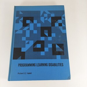 Op de afbeelding: Een blauw boek met een geometrisch patroon op de omslag. De titel is "Programming Learning Disabilities" door Robert E. Valett.
