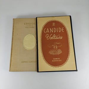 May include: Two vintage books titled "Candide" by Voltaire. The book on the left has a tan cover with gold lettering and a gold oval emblem. The book on the right has a dark brown cover with the title in a decorative oval and the words "Cameo Classics".