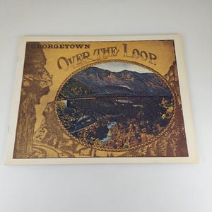 Peut inclure: Carte postale vintage représentant Georgetown Over the Loop. L'image montre un train traversant un pont au-dessus d'un canyon, avec des montagnes en arrière-plan. La carte postale a un fond sépia avec les mots "Georgetown Over The Loop" dans une police décorative.