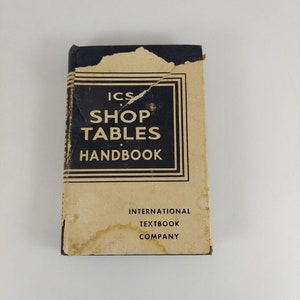 May include: A vintage brown and blue book titled "ICS Shop Tables Handbook" by International Textbook Company.
