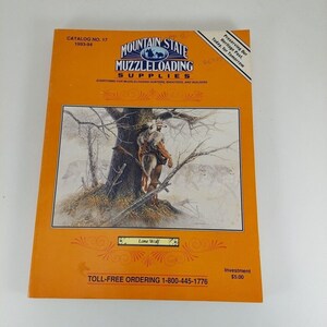 Puede incluir: Una portada de catálogo vintage de color naranja y blanco para Mountain State Muzzleloading Supplies. La portada presenta una pintura de un lobo solitario en un bosque nevado. El texto de la portada dice "Catalog No. 17 1993-94 Mountain State Muzzleloading Supplies Everything for Muzzleloading Hunters, Shooters, and Builders." El texto en la parte inferior de la portada dice "Lone Wolf Investment 5,00 €  Número de teléfono gratuito 1-800-445-1776."