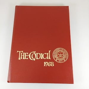 May include: A red hardcover book titled "The Codici" with gold lettering and a university seal. The year "1968" is printed below the title. The book is closed and lies flat.
