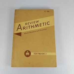 May include: A tan-colored textbook titled "Review Arithmetic" with the subtitle "Whole Numbers and Fractions". The book is labeled "Textbook I" and has a small insignia with the letters "USAF" on the cover.