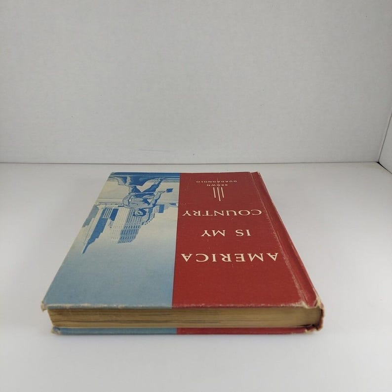 Puede incluir: Un libro rojo y azul con el t&iacute;tulo "AMERICA IS MY COUNTRY" y el autor "HARVARD  CLASSICS" en el lomo.