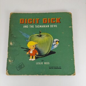 May include: A green book cover with the title "Digit Dick and the Tasmanian Devil" in red and white letters. The book cover also features a cartoon illustration of a boy, a green apple, and a blue bird.