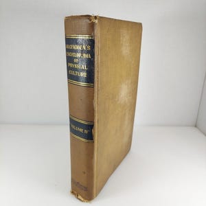 May include: A vintage book titled "Macfadden's Encyclopedia of Physical Culture, Volume IV." The book has a worn, tan cover with a dark blue spine and gold lettering. The spine displays the title and volume number. The book's edges show signs of age.