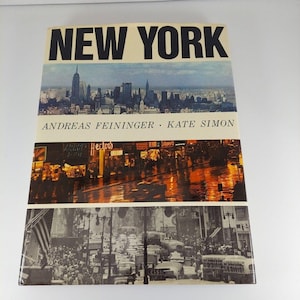 Puede incluir: Un libro de tapa dura vintage titulado "Nueva York" de Andreas Feininger y Kate Simon. La portada presenta tres imágenes de la ciudad de Nueva York: una vista panorámica del horizonte, una escena callejera nocturna con letreros de neón y una calle concurrida con coches y peatones.