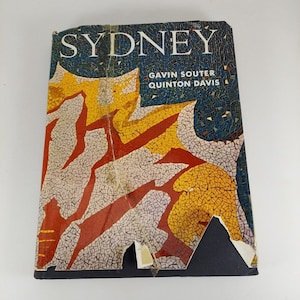 May include: A book titled "Sydney" by Gavin Souter and Quinton Davis. The cover features a colourful mosaic design in shades of red, yellow, and blue.