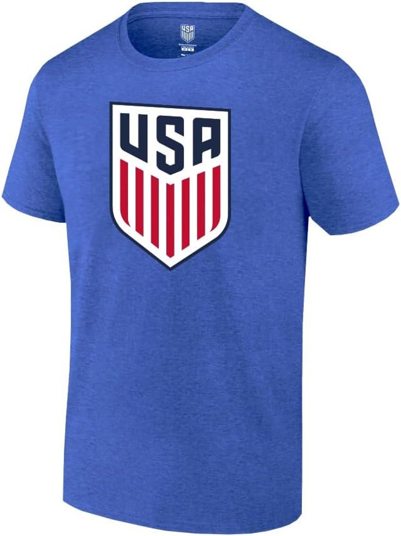 May include: A royal blue t-shirt with a white and red USA crest graphic. The crest features a shield with the letters USA and red and white stripes.