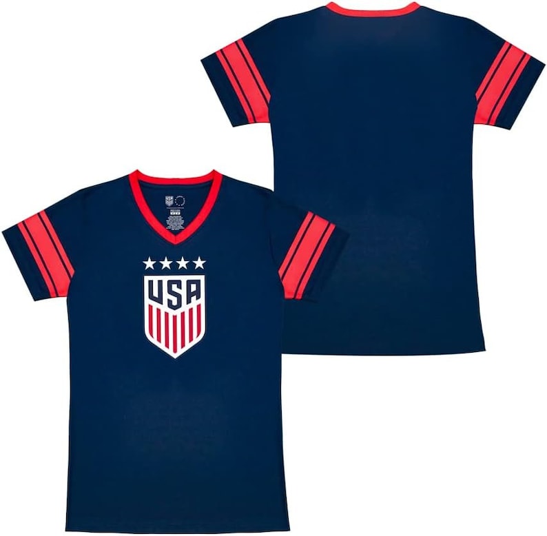 May include: A navy blue t-shirt with red and white stripes on the sleeves. The front of the shirt features a white "USA" logo with five stars and a shield design.