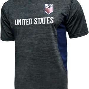 May include: A dark gray and navy blue short-sleeved t-shirt with a white "UNITED STATES" text and a red, white, and blue "USA" logo on the front.