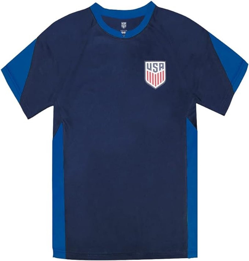 May include: A navy blue short-sleeved t-shirt with blue side panels. The shirt has a white crew neck and a small embroidered USA crest on the front.