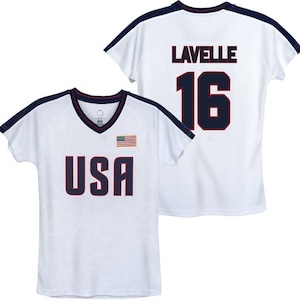 May include: White t-shirt with a navy blue trim and the words "USA" and a small American flag on the front. The back of the shirt has the name "Lavelle" and the number "16" in navy blue.