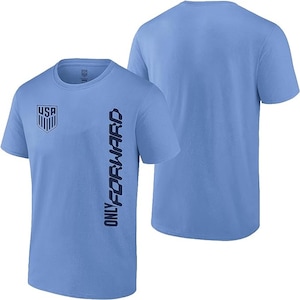 K&ouml;nnte beinhalten: Hellblaues T-Shirt mit einem dunkelblauen USA-Wappen auf der linken Brust und dem Text "ONLY FORWARD", der vertikal auf der rechten Seite aufgedruckt ist.