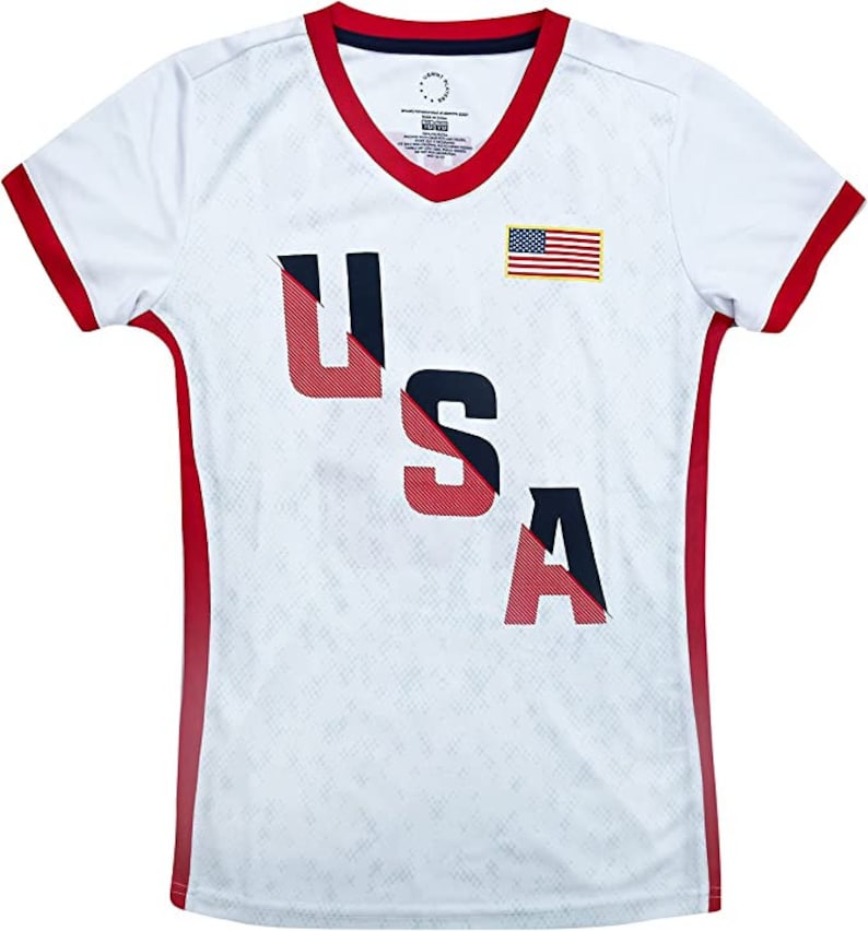 May include: White short-sleeved jersey with red and blue trim. The jersey has a diagonal red and blue stripe with the word "USA" in red and blue letters. A small American flag is on the right side of the jersey.