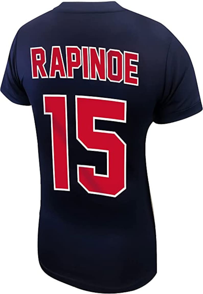 May include: A navy blue jersey with the name "RAPINOE" and the number "15" printed on the back in red with white outlines.