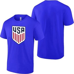 Pode incluir: Uma camiseta azul royal com um bras&atilde;o branco dos EUA com listras vermelhas e brancas. O bras&atilde;o est&aacute; centralizado na frente da camiseta.