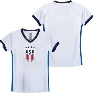Peut inclure: Maillot de football blanc avec des bordures bleues et le logo des &Eacute;tats-Unis sur le devant. Le maillot a un col en V et des manches courtes.