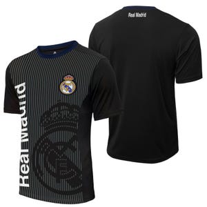 May include: Black short-sleeved t-shirt with a white and gray Real Madrid logo and the text "Real Madrid" printed vertically on the left side. The back of the shirt has the text "Real Madrid" printed in white.