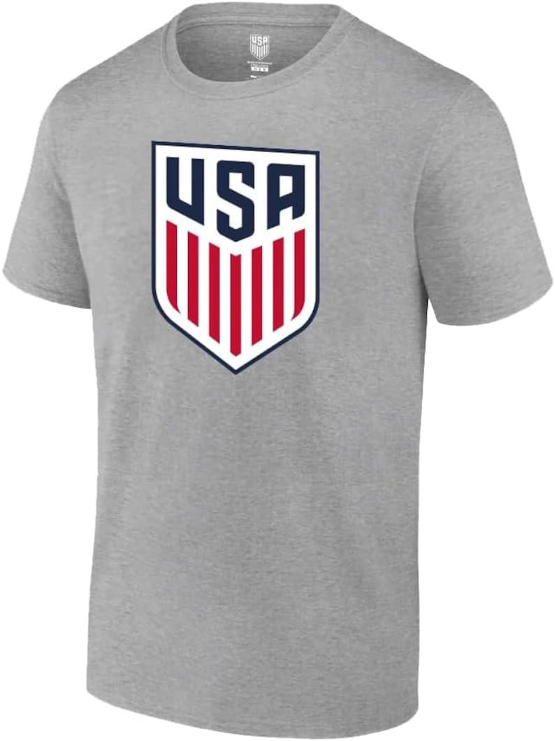 May include: A gray t-shirt with a navy blue and red USA logo on the front. The logo is a shield with the word "USA" in white letters and red and white stripes.