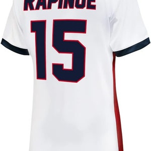 May include: White soccer jersey with a navy blue and red trim. The back of the jersey has the name "RAPINOE" and the number "15" in navy blue.