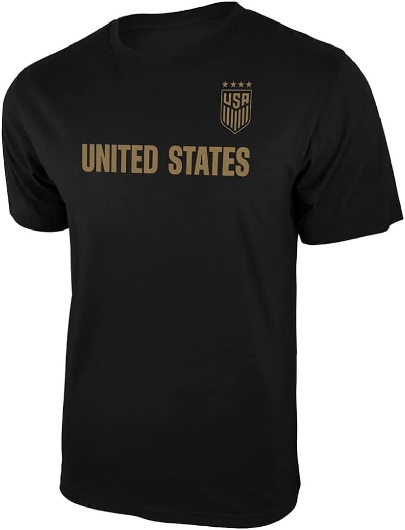 May include: Black t-shirt with a gold graphic of the United States soccer team logo and the words "UNITED STATES".