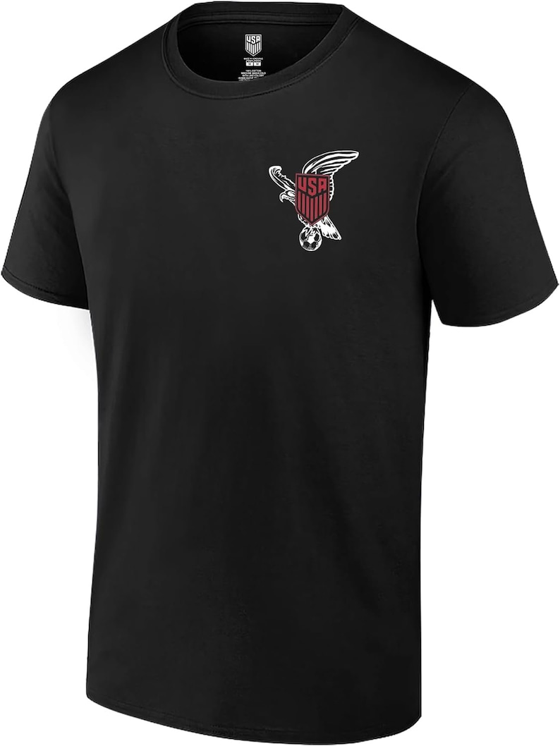 May include: Black t-shirt with a white graphic of an eagle holding a soccer ball. The eagle is holding a shield with the word "USA" on it.