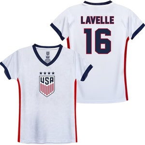 May include: White soccer jersey with red and navy blue trim. The front of the jersey has a USA logo with stars and stripes. The back of the jersey has the name "Lavelle" and the number "16" in navy blue.