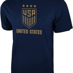 Puede incluir: Una camiseta azul marino con un gr&aacute;fico dorado de la bandera de los Estados Unidos y el texto "UNITED STATES".