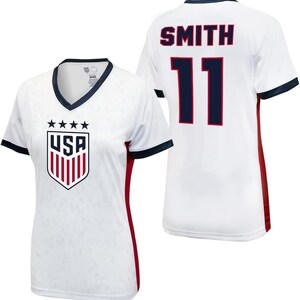K&ouml;nnte beinhalten: Wei&szlig;es Fu&szlig;balltrikot mit roten und dunkelblauen Akzenten. Das Trikot hat das USA-Wappen auf der Vorderseite und den Namen "SMITH" und die Nummer "11" auf der R&uuml;ckseite.